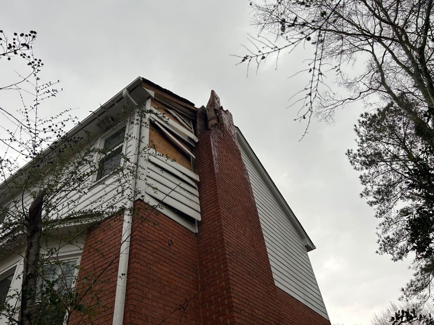 Exterior structural damage near chimney and roofline following impact