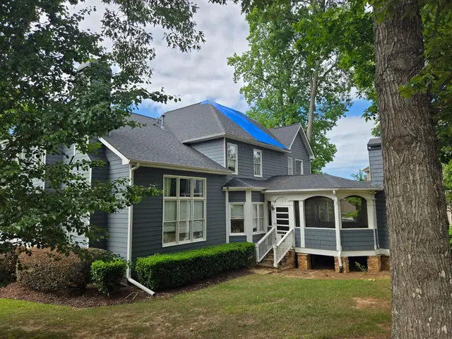 Residential property with emergency roof tarp installed after storm damage