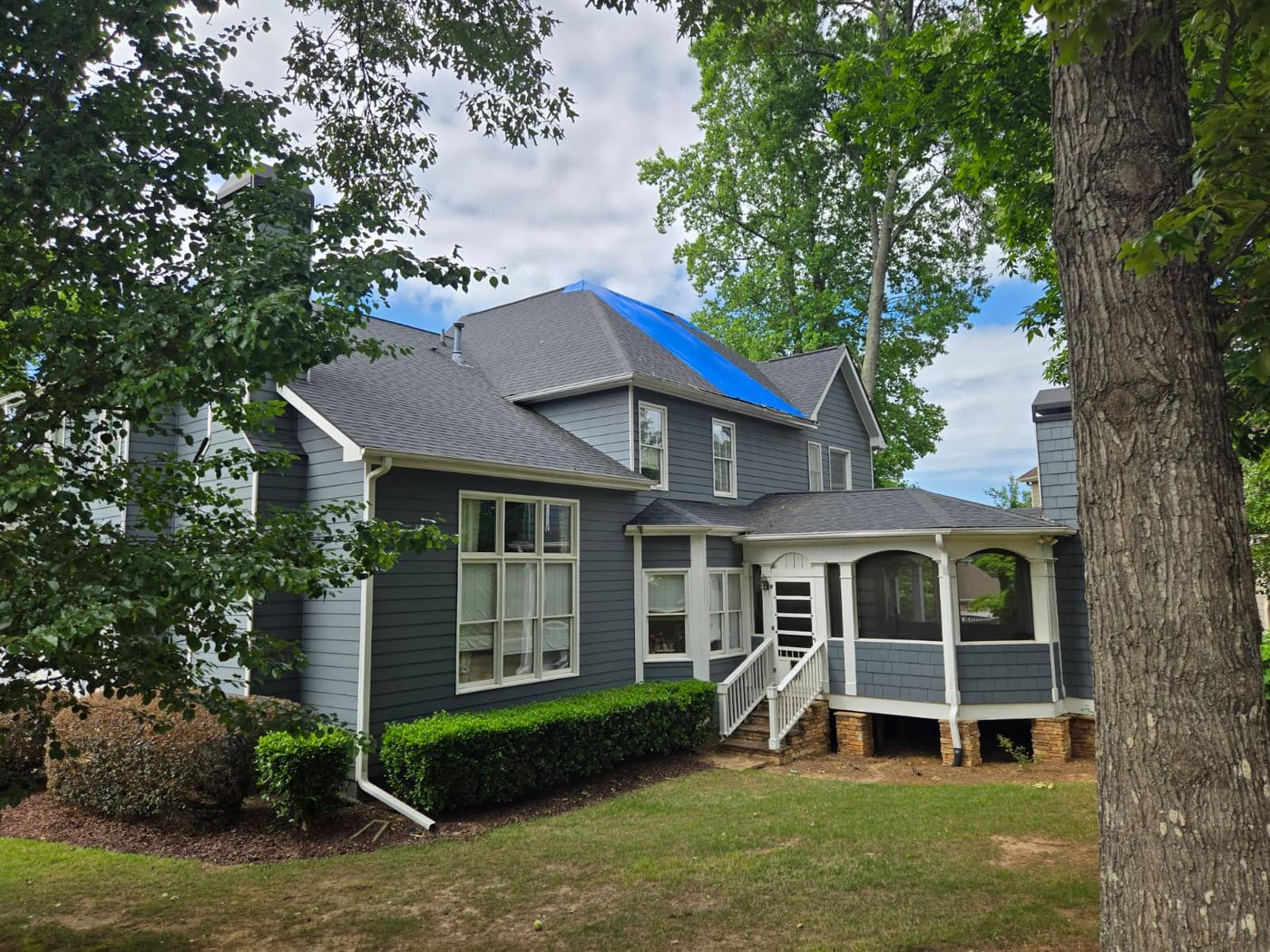 Residential property with emergency roof tarp installed after storm damage
